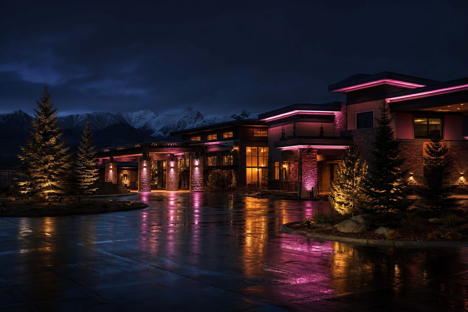 Casino resort exterior at night with pink neon lighting and snowy mountains behind